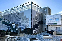 Mehrstöckiges Parkhaus mit moderner Fassade aus horizontalen Lamellen und angrenzendem Gebäude mit Schriftzug 'Sanitätshaus Schwabstraße 2a b c d'