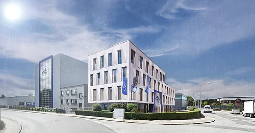 Modernes Bürogebäude mit Glasfassade und weißer Außenverkleidung an einer Straßenecke unter blauem Himmel