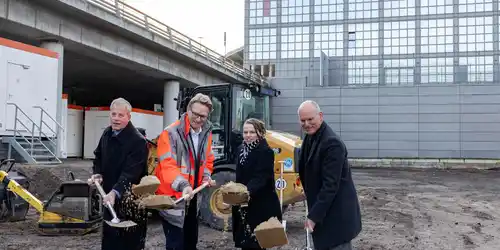 Symbolischer Spatenstich durch Marc Johannes, Christian Kunsch, Dr. Melanie Leonhard, Jörn Johannes Vier Personen in Winterkleidung führen einen symbolischen Spatenstich auf einer Baustelle vor einem modernen Gebäude durch