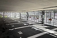 Leerer überdachter Parkplatz mit markierten Stellflächen und Metallgeländer an der Seite