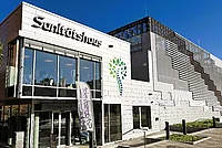 Modernes Gebäude mit der Aufschrift 'Sanitätshaus' und einem stilisierten Baumlogo neben dem Eingang